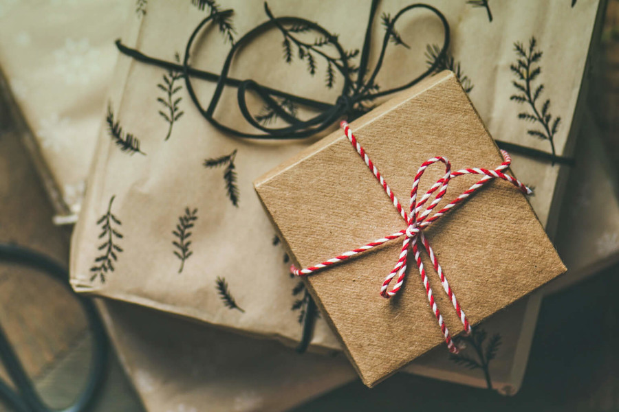 Weihnachtspäckchen in braunem Kraftpapier mit rot-weitem Band